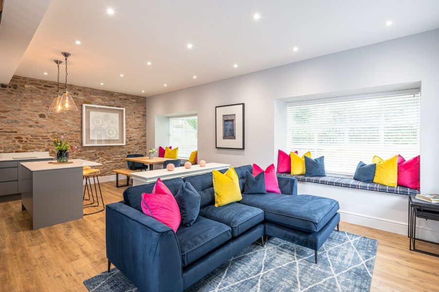 Modern open-plan living area with blue sofa and colourful cushions in The Old Tack Room.