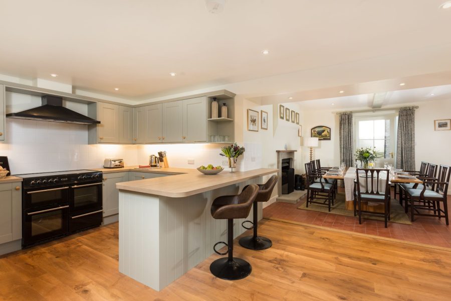 Modern kitchen with bar stools, island and dining area at Hollins Farmhouse.