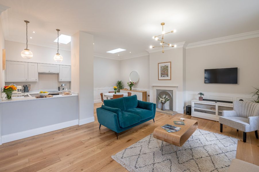 The Swaledale spacious open-plan living area with teal sofa, feature fireplace and modern kitchen.
