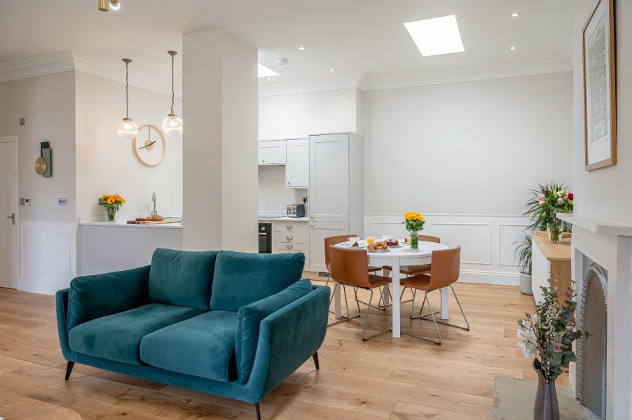 The Swaledale open-plan living and dining area with velvet sofa, round table and bright skylights.