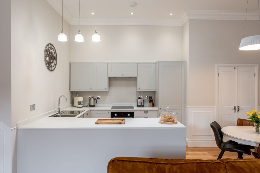The Wensleydale modern kitchen with grey cabinetry, integrated appliances and breakfast bar with pendant lighting.