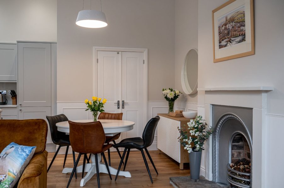 The Wensleydale open-plan dining area with round table, leather chairs, decorative fireplace and soft neutral decor.
