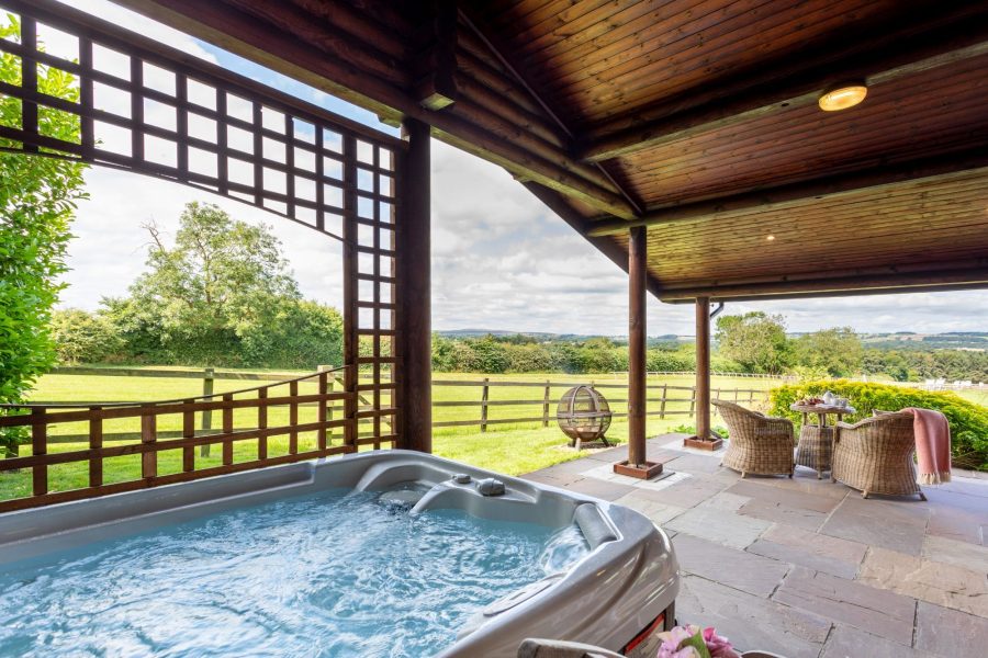Covered outdoor hot tub with countryside views at Spindrifter luxury holiday lodge.