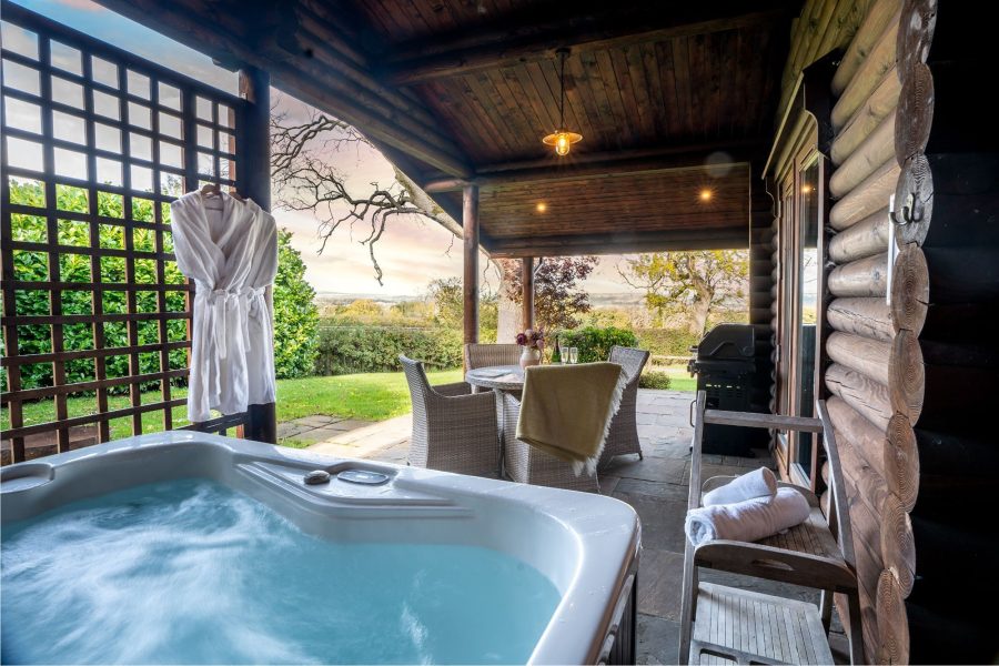 Private outdoor hot tub at Alborada cabin with covered terrace and countryside views.