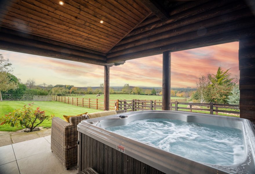 Covered outdoor terrace at Melody lodge with hot tub and countryside views.