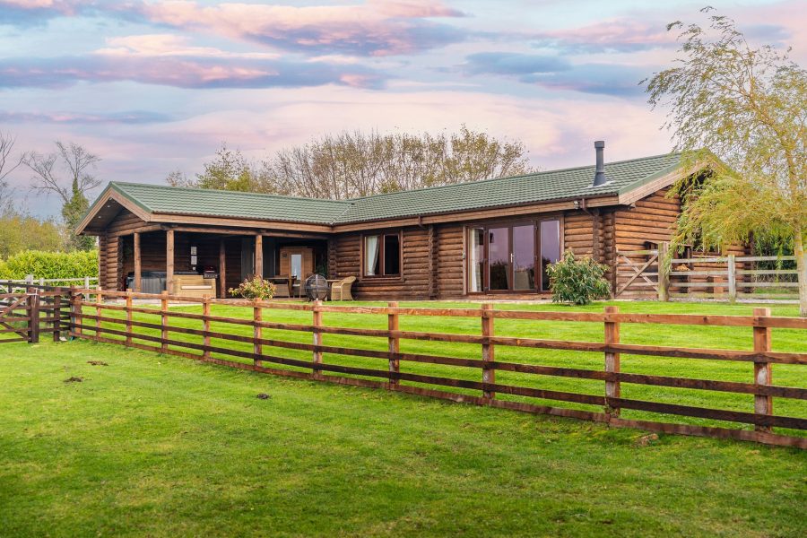 Exterior of Melody lodge, a wooden log cabin with patio, garden lawn and countryside views at Sun Hill Lodges.