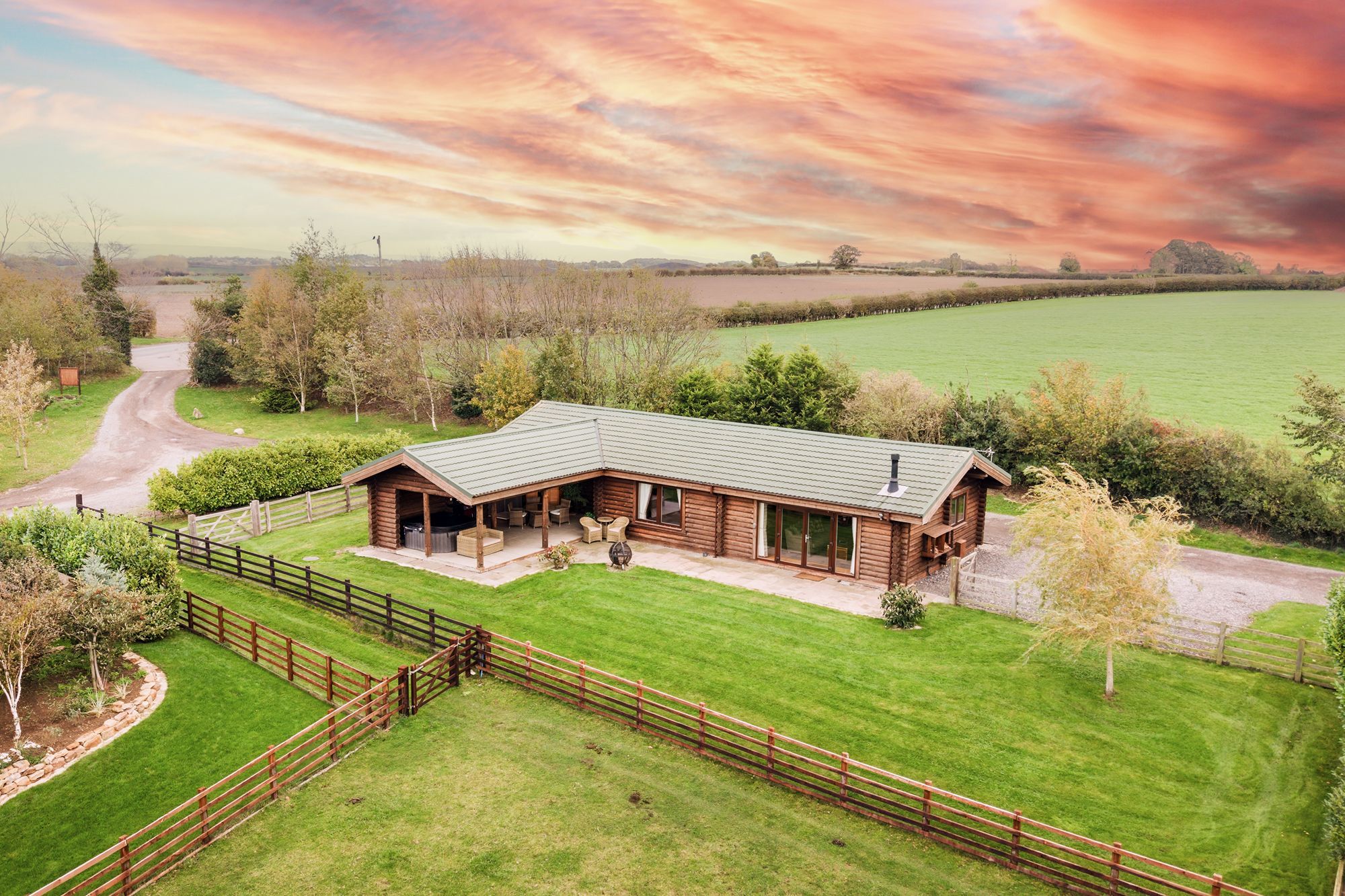Exterior of Melody lodge, a wooden log cabin with patio, garden lawn and countryside views at Sun Hill Lodges.
