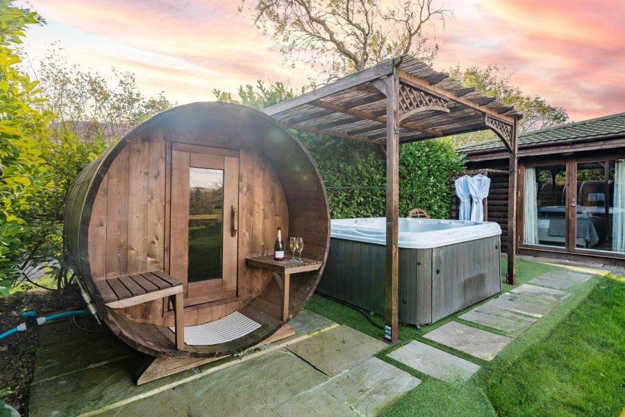 Outdoor spa area at William lodge with barrel sauna and covered hot tub in private garden.