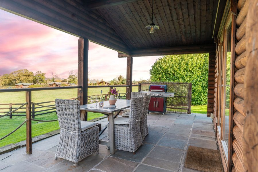 Covered outdoor dining area at William lodge with table, chairs and barbecue grill.