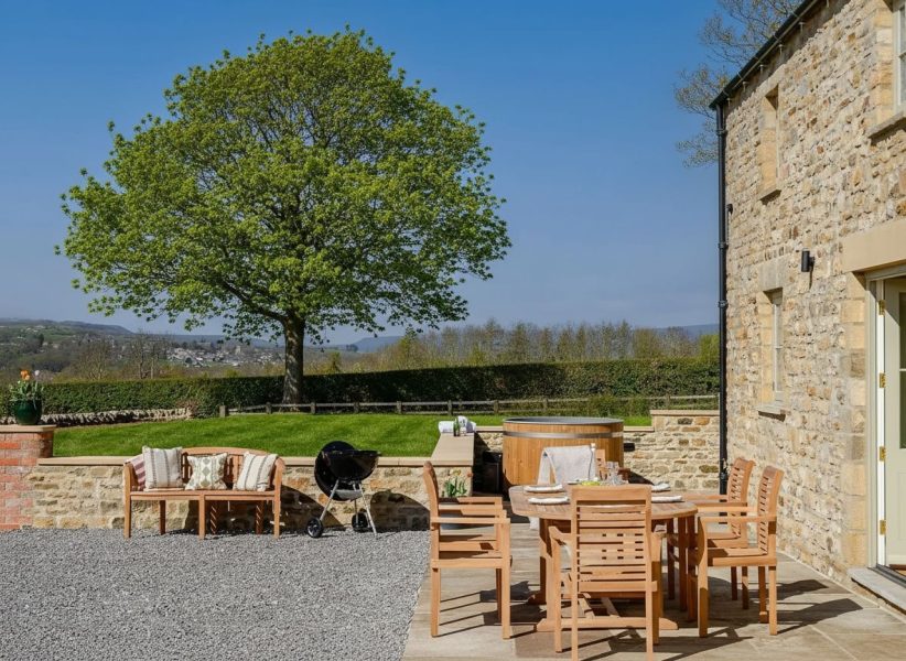 Hollins Barn in North Yorkshire, a luxury stone barn with outdoor dining area and traditional Yorkshire architecture.
