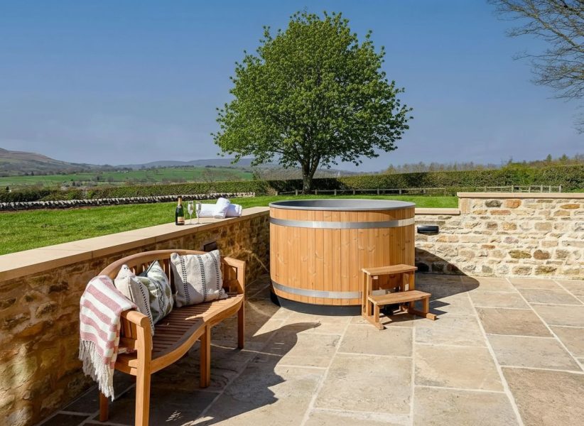 Private patio with seating and jacuzzi-style hot tub at Hollins Barn.