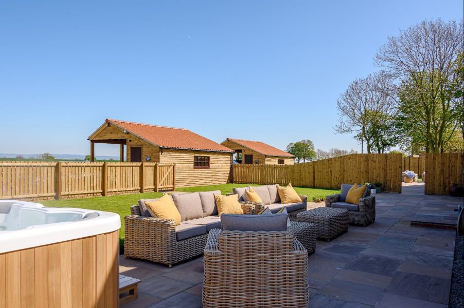 Wheatsheaf Barn outdoor rattan seating area with hot tub and scenic countryside views.