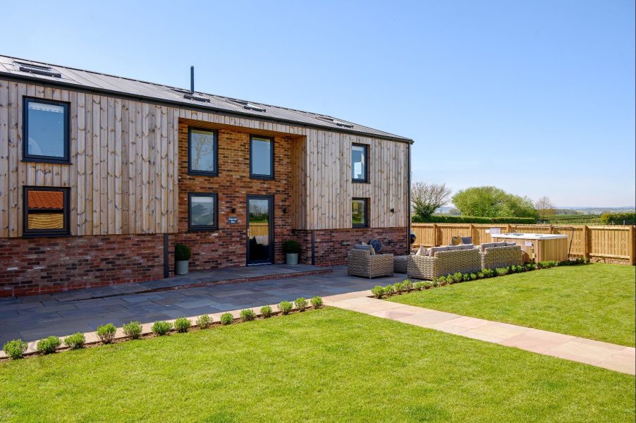 Exterior of Wheatsheaf Barn, a spacious holiday home with large lawn, patio, and rural countryside setting.