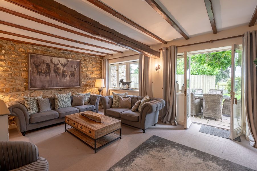 Cosy living room with stone wall and patio doors at Sun Hill Cottage.