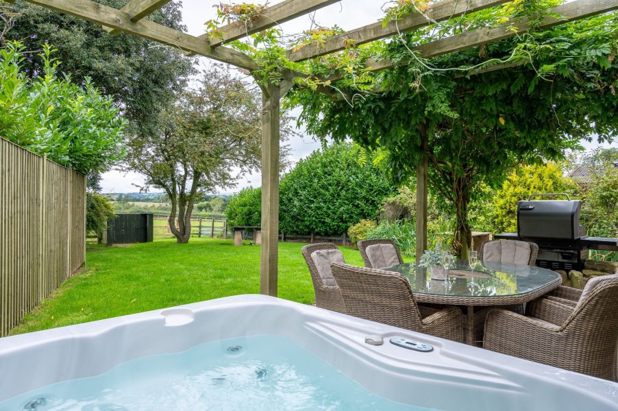 Garden with covered private hot tub and countryside views at Sun Hill Cottage in North Yorkshire.