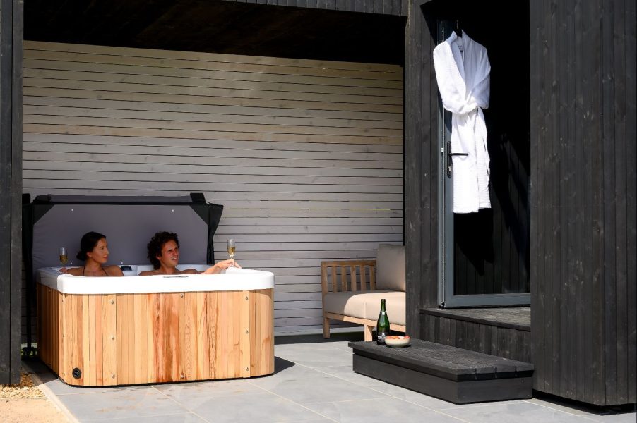 Couple in a hot tub at a Scandinavian-style lodge, at Greenbank Lodges
