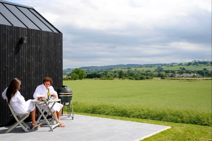 Couple in robes sitting outside at Greenbank Lodges looking at the view. 