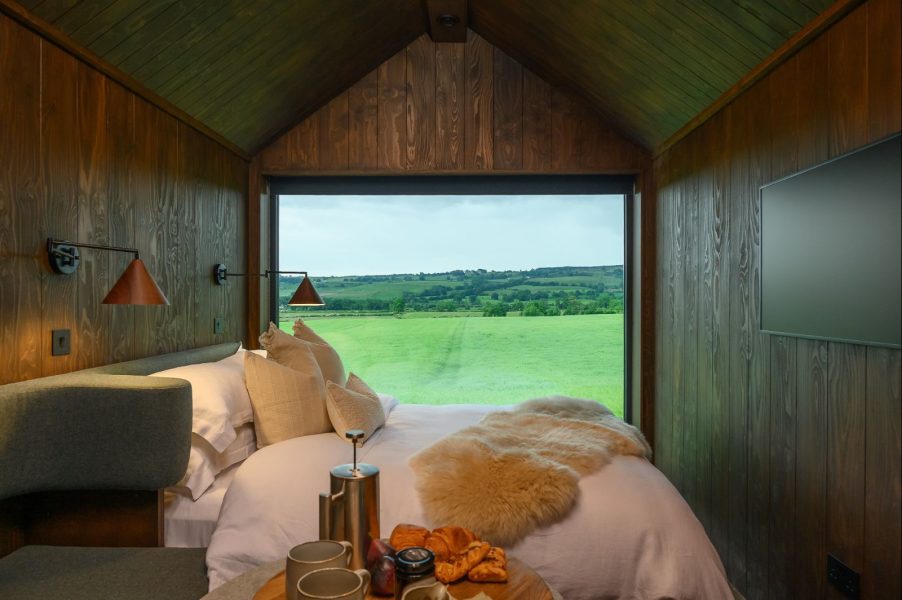 Luxury studio bedroom in Elvar Lodge, North Yorkshire, featuring panoramic countryside views through a floor-to-ceiling window.