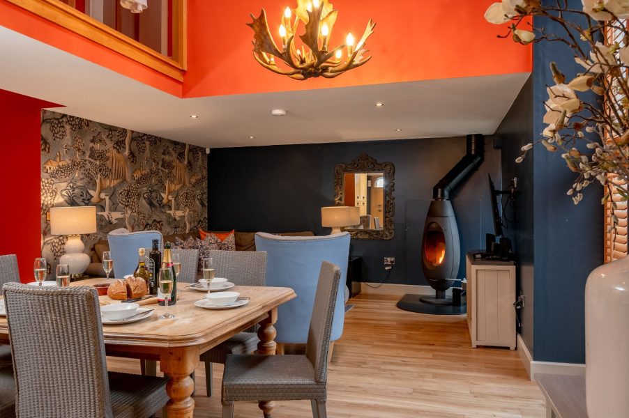 Open-plan dining and living area with wood burner, large table and cosy seating in Georgia cottage.