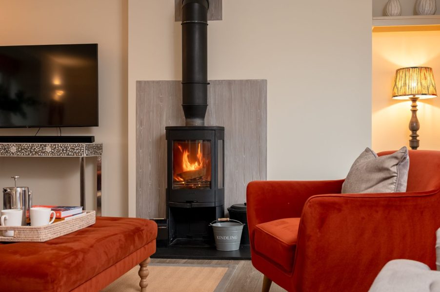 Wood burning stove with cosy seating and warm lighting in Henry cottage at Holly House Farm.