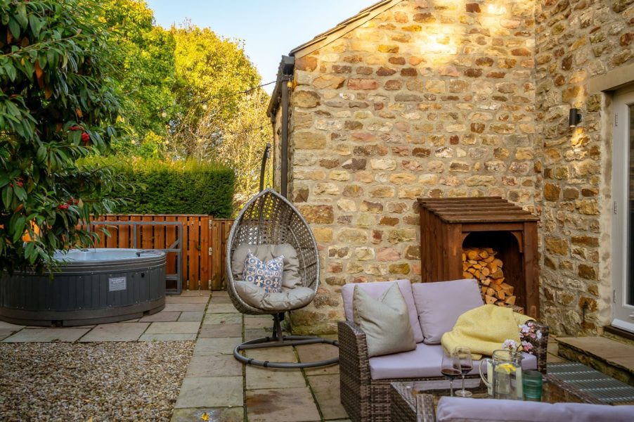 Private cottage patio with hot tub, outdoor seating and hanging chair in peaceful countryside setting at Holly House Farm.