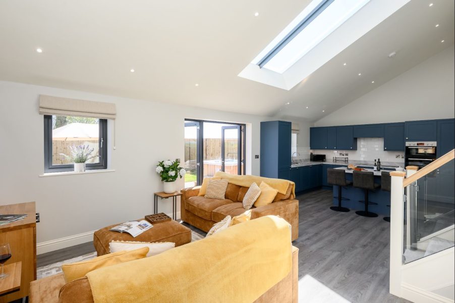 Field Cottage open-plan living area with sofas, skylight, and modern blue kitchen.