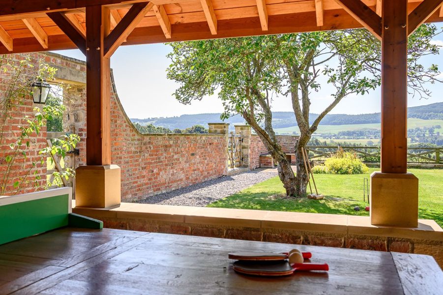 Covered outdoor games area at Hollins Farmhouse with table tennis, croquet lawn and panoramic Peak District countryside views.