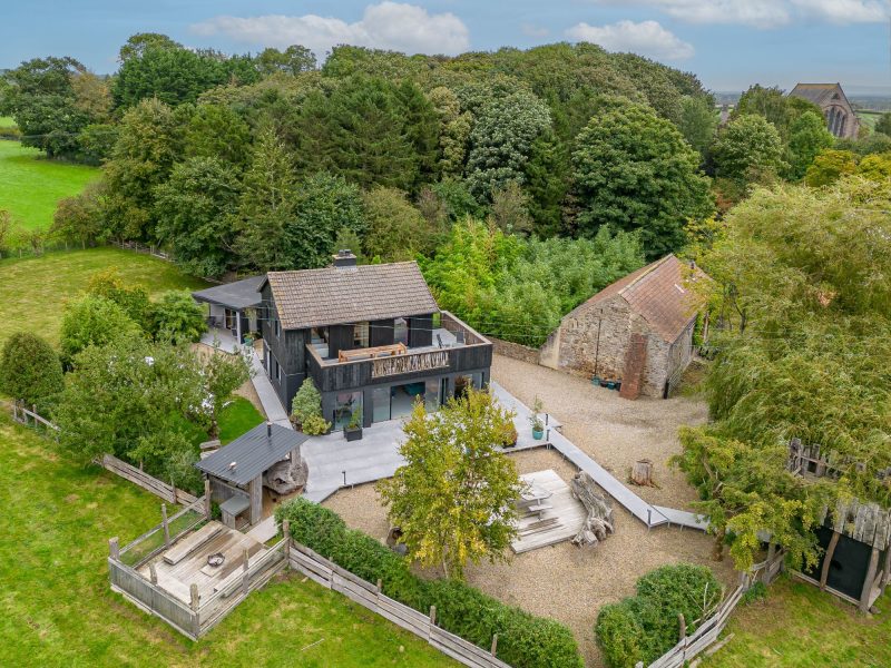 Modern countryside cabin with large terrace, outdoor seating area and surrounding gardens.