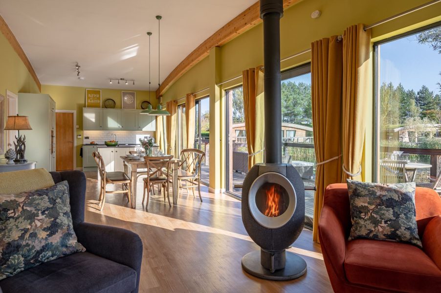 Open-plan kitchen, living and dining area with floor-to-ceiling windows in Florence lodge at Brompton Lakes with lakeside views.