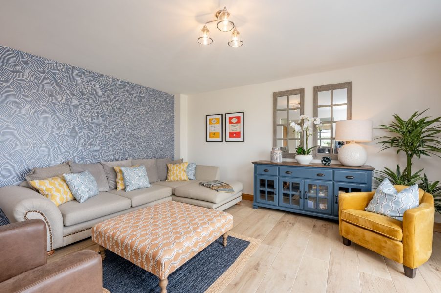 Stylish living room in Ellesmere Barn holiday cottage with corner sofa, patterned feature wall and contemporary furnishings.