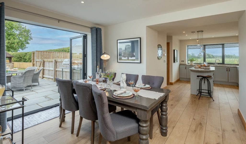Ellesmere Barn open-plan dining area with table setting, patio doors to garden and adjoining modern kitchen.