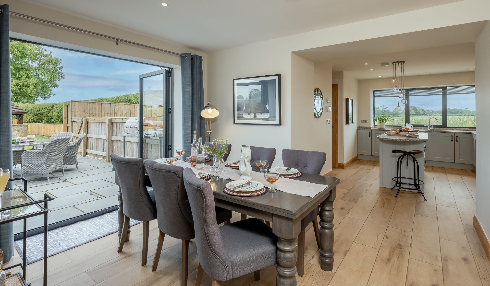 Ellesmere Barn open-plan dining area with table setting, patio doors to garden and adjoining modern kitchen.