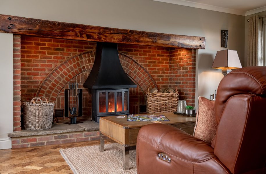 Cosy living room with wood-burning stove and exposed beams at Harelands holiday cottage.