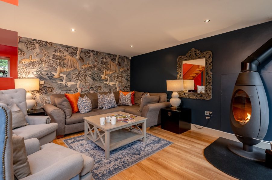 Stylish living room with wood burner in Georgia cottage with cosy sofas and feature wallpaper.
