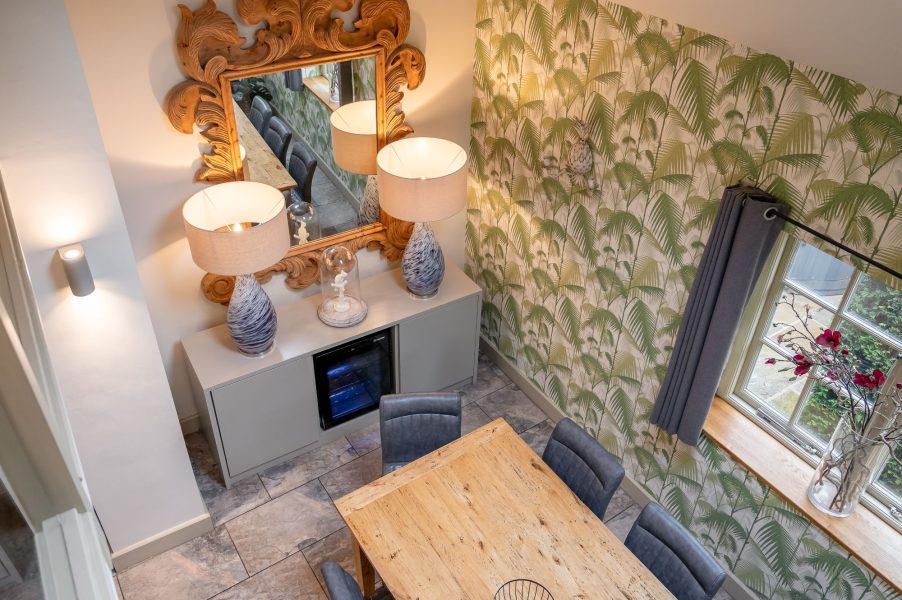 Bright dining area with feature wallpaper and wooden table in Henry cottage.