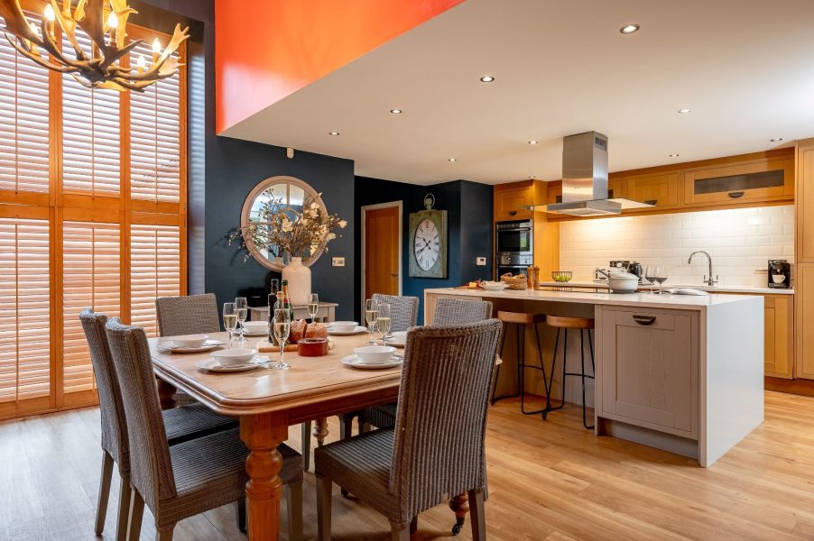Open-plan kitchen and dining area with island in Georgia cottage with wooden table and modern appliances in self-catering holiday home.