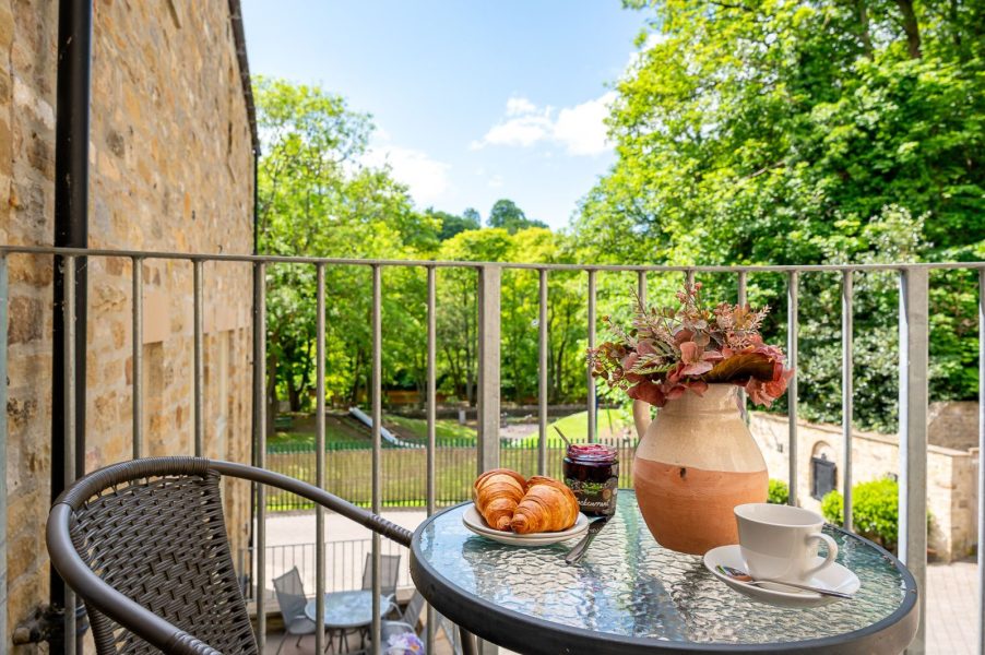 Darcy Mews private balcony with bistro table and seating, enjoying peaceful garden views, perfect for morning coffee with fresh pastries in a tranquil setting.
