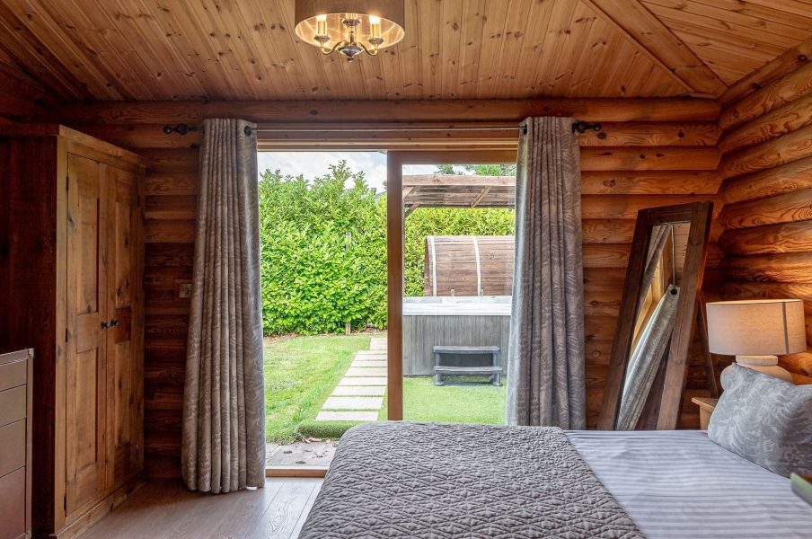Spacious bedroom in William lodge with dresser, wall-mounted TV and patio doors to garden.