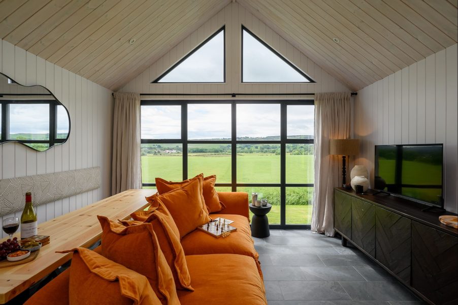 Open-plan living area at Olof lodge in North Yorkshire with floor-to-ceiling windows overlooking rolling North Yorkshire countryside views.