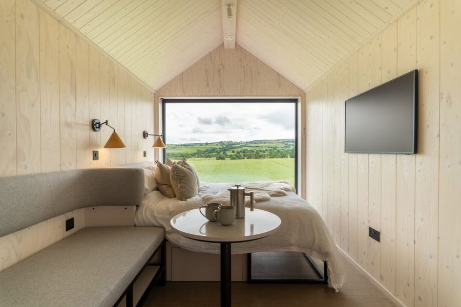 Luxury lodge bedroom with king-size bed and panoramic Yorkshire countryside views through a floor-to-ceiling picture window.