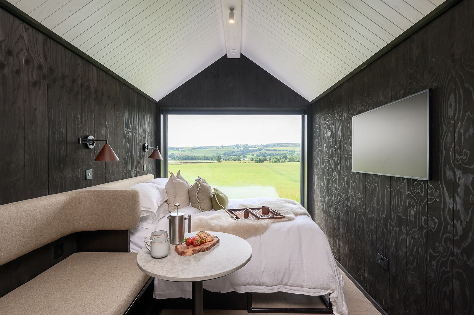 Dark Scandinavian lodge bedroom with panoramic countryside views across North Yorkshire