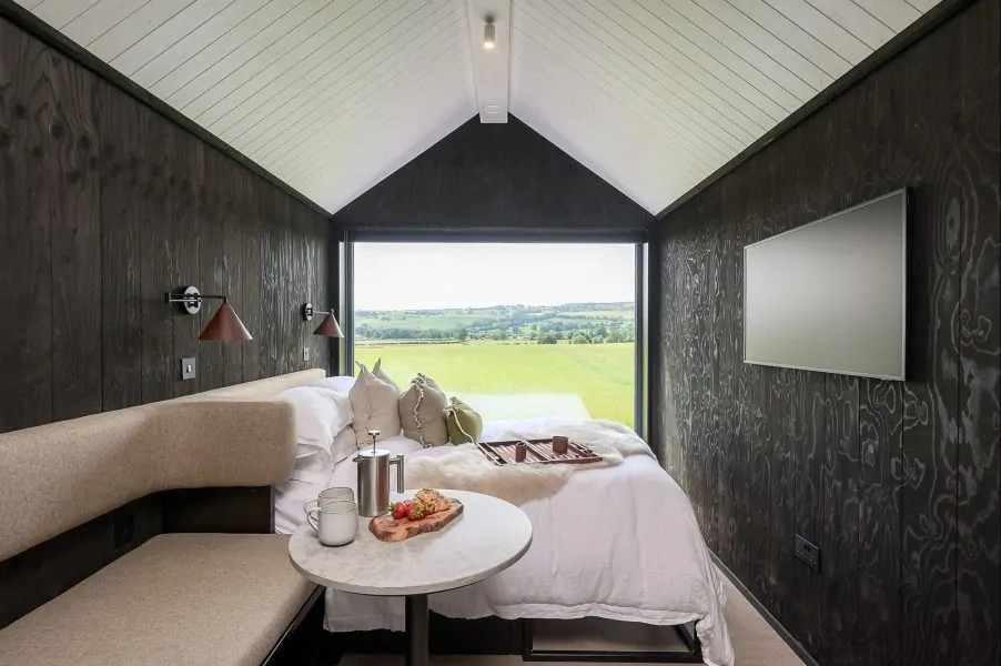 Dark Scandinavian lodge bedroom with panoramic countryside views across North Yorkshire
