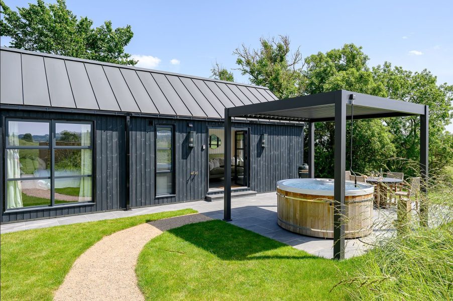 Private outdoor hot tub at Ake lodge in North Yorkshire overlooking rolling countryside views from a covered terrace.