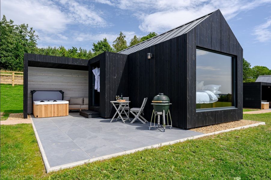 Exterior of Ylfa lodge, a luxury black-timber cabin in North Yorkshire with privat epatio, hot tub, BBQ and countryside setting.