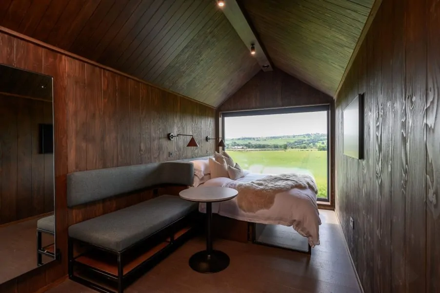 Luxury lodge bedroom in Ylfa lodge with king-size bed and panoramic Yorkshire countryside views through a floor-to-ceiling window.