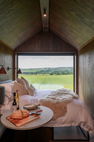 Scandi-style studio lodge with king size bed and panoramic countryside views through a floor-to-ceiling picture window.