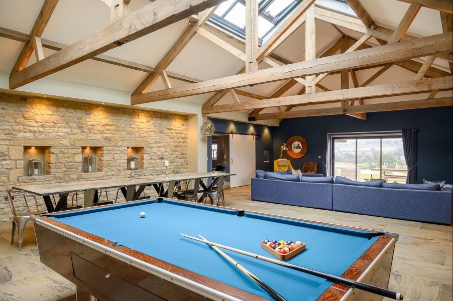 Open-plan living area with pool table, large dining table, comfy sofas, high ceilings and countryside views at Dexter.