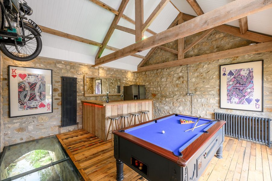 Games room in Kingfisher holiday cottage with pool table, bar area, exposed stone walls and vaulted beams.