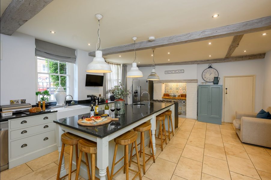 Kitchen at 30 Frenchgate with a large island and bar stools, pendant lights, and an inglenook-style cooker alcove with patterned tiles.