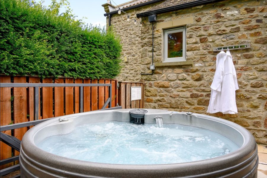 Evening courtyard with jacuzzi-style hot tub and fairy lights at Georgia cottage.